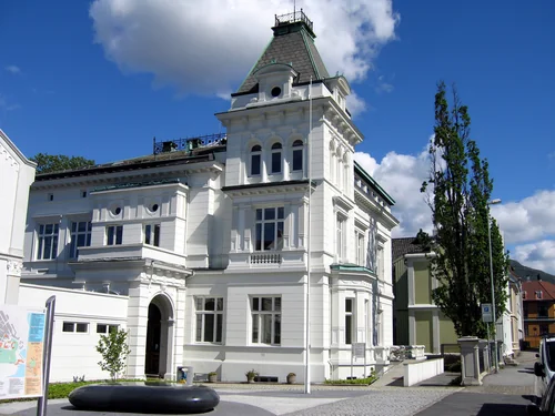 White villa with a turret and an arched entrance under a bright blue sky