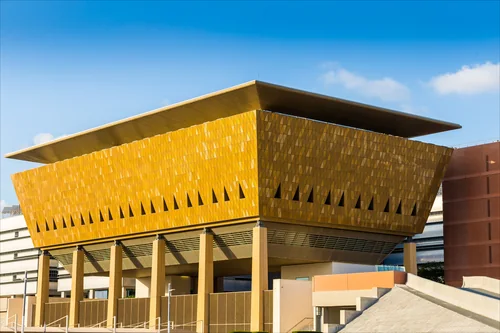 Golden block on columns under a flat overhanging roof against a blue sky