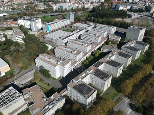 Aerial view of rows of white teaching blocks with solar panels among trees