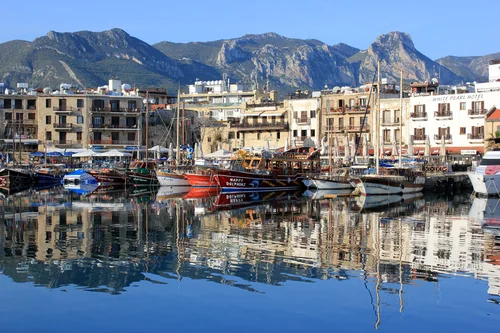 Harbour with pleasure boats, stone waterfront houses and a mountain ridge behind