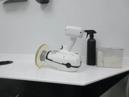 White handheld X-ray unit on a countertop beside a spray bottle and a box of cotton rolls