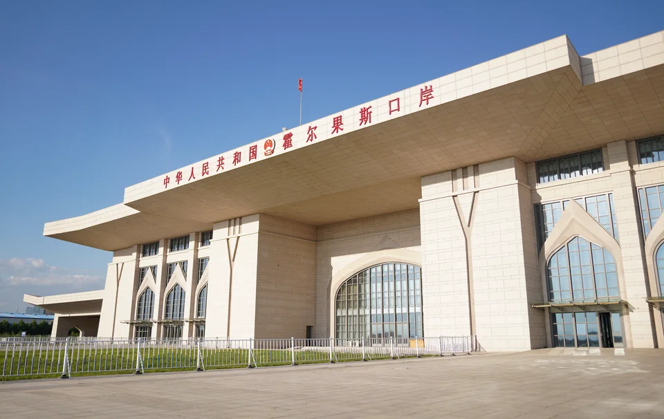 Светлое здание пограничного перехода с красной надписью на китайском и арочными окнами