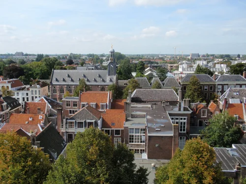 A panorama of tiled roofs and brick houses of an old town with a bell tower and a plain in the distance