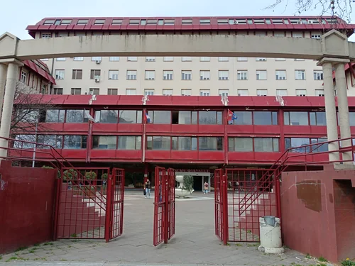 Entrance with red railings and open gates in front of a multi-storey building