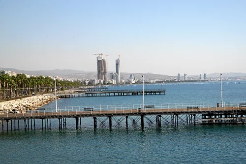 Wooden piers in the sea, a palm-lined promenade and high-rises along the coast