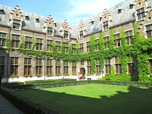 Brick courtyard with stepped gables, ivy-covered walls and a lawn in the middle
