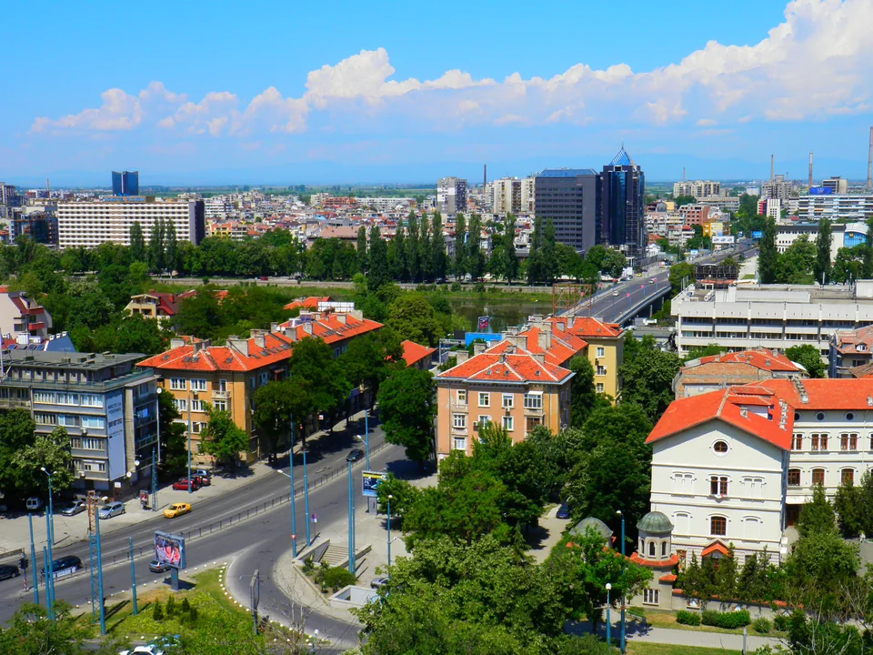 Городские кварталы с красными крышами, проспект с мостом и высотки на горизонте
