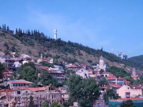 Hillside of old Tbilisi houses and churches with a statue on the crest