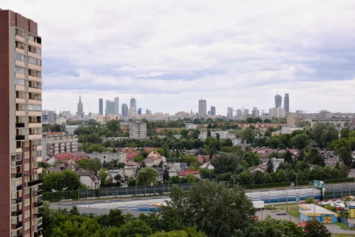 A distant skyline of high-rises and the Palace of Culture, with leafy low-rise neighbourhoods closer and a tower block on the left