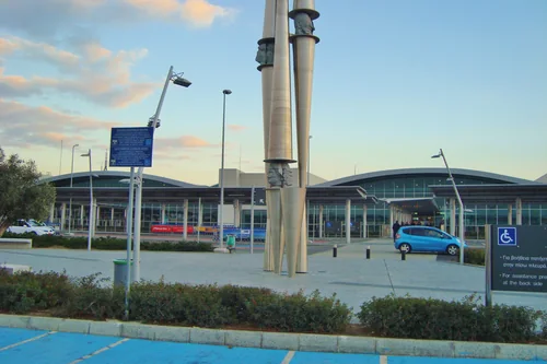 Terminal façade with a wave-shaped roof and a metal sculpture on the forecourt