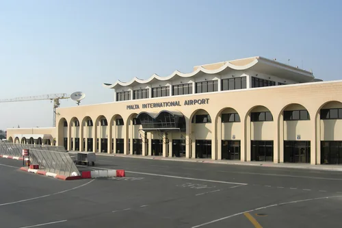 Pale airport building with an arched arcade and the Malta International Airport sign