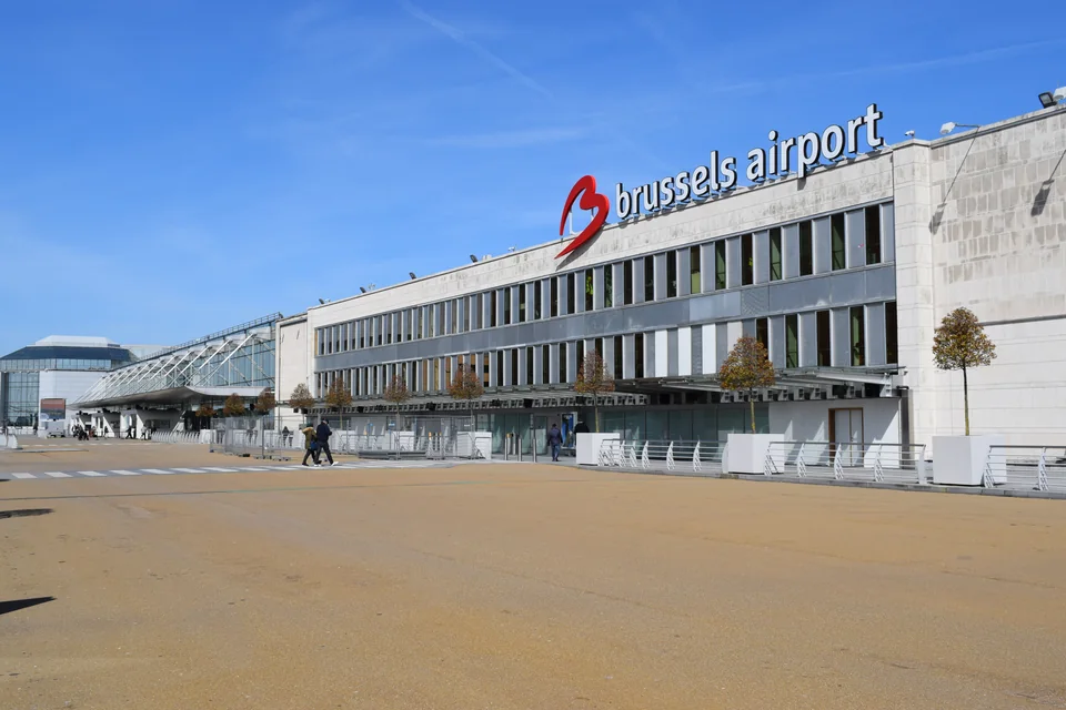 Длинное здание терминала с вывеской brussels airport и пустой площадью перед ним