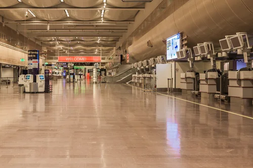 Empty departures hall with self-service check-in kiosks and a glossy floor