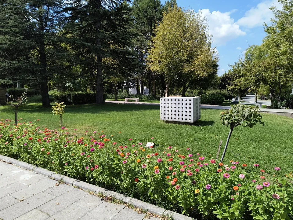 Клумбы и деревья в кампусе Beytepe, за ними белая кубическая скульптура с круглыми отверстиями