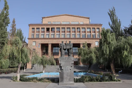Pink tuff building with a monument of two figures holding a book and weeping willows