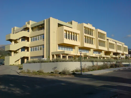 Terraced pale-yellow building with ribbon windows under a blue sky
