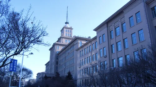 Grey-blue building with a spired tower, bare branches on the left