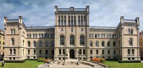 Symmetrical brick neo-Renaissance façade with a central tower and a garden in front