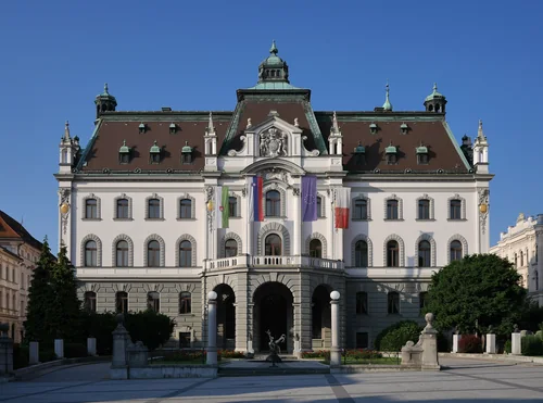 White palace with a dome, flags and an arched entrance under a blue sky