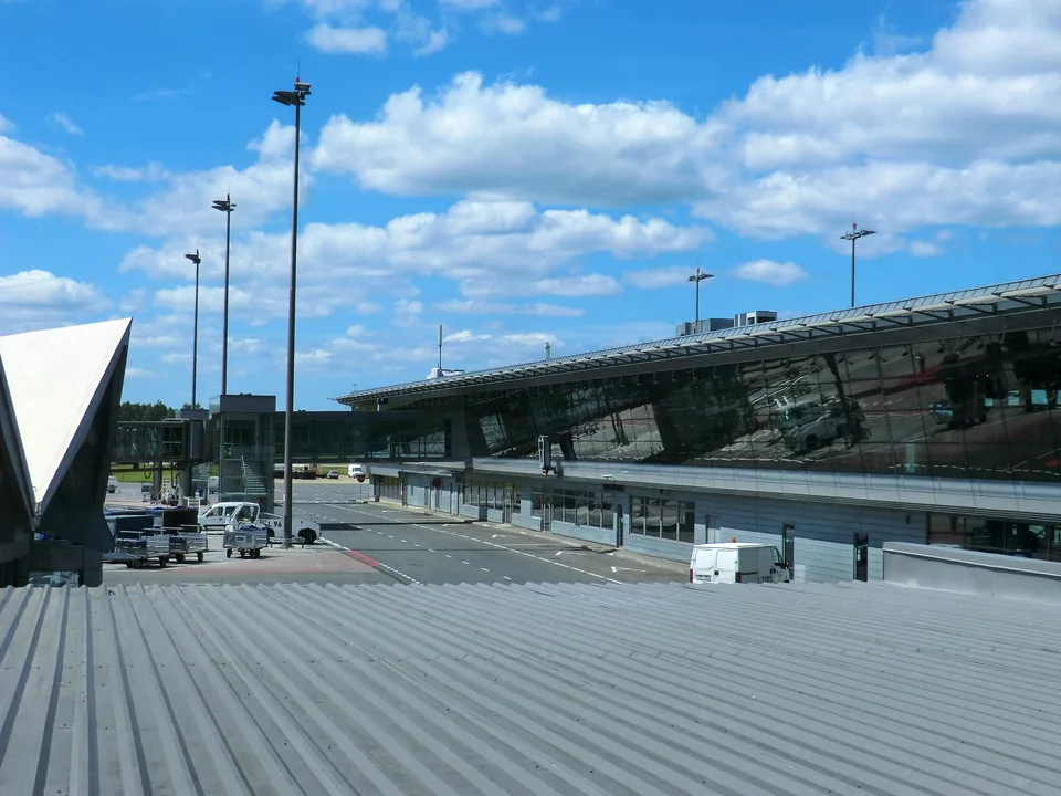 Стеклянный терминал с перроном и мачтами освещения под облачным небом