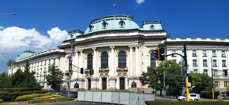 Здание с зелёным куполом и колоннами на перекрёстке с сквером